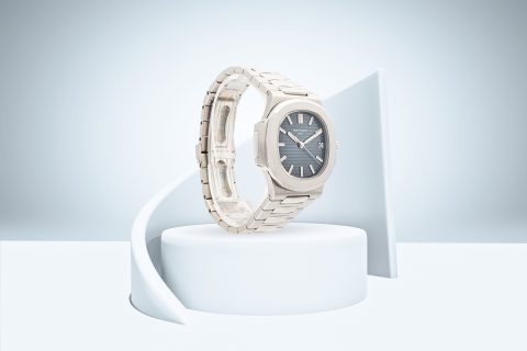 Patek Philippe Nautilus with grey dial and white gold case displayed on a minimalist white pedestal.